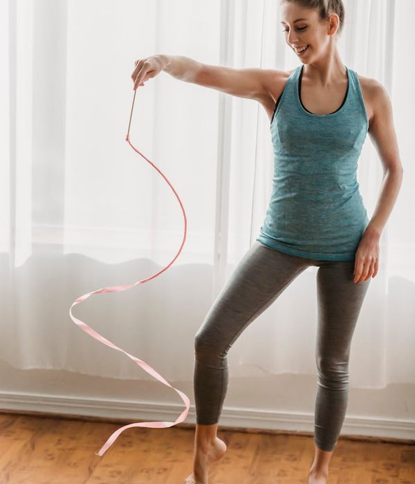 Woman performing a light aerobic movement in a calm, modern space.
